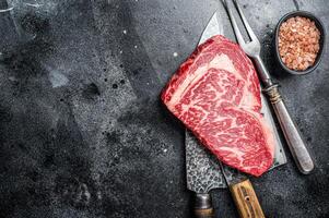 Butcher table with wagyu Rib Eye steak, raw beef meat. Black background. Top view. Copy space photo