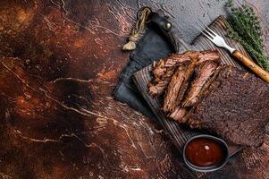 Traditional smoked barbecue wagyu beef brisket on wooden board. Dark background. Top view. Copy space photo