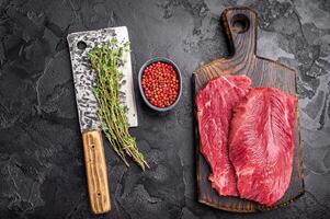 Raw Boar meat steak, uncooked Game Meat on cutting board. black background. top view photo