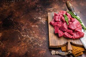 Diced Raw Venison meat, fresh Wild Roe Deer Game Meat on butcher cutting board. brown background. top view photo
