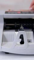 Electronic device is calculating fifty-euro bills. Woman puts paper banknotes into automatic counting machine. Automatic mechanism for bank financial operations. Currency exchange. Vertical video
