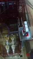 Metal tower constructions with ladders climbing up to the tops of elevator tanks. Silo elevator from the bird's eye view. Vertical video