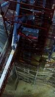 High construction towering over the granary elevator tanks. Flying over the silo complex. Ground covered with snow at backdrop. Vertical video