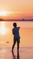 Child playing paper airplane. Joyful caucasian funny boy plays and enjoys in the river Vertical video