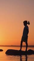 Boy resting in pond. Silhouette a boy with rocket paper in the sunset Vertical video