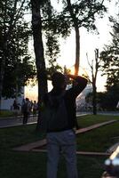 The Silhouette of a Photographer Capturing Moments at Sunset in a Tranquil Park Setting photo