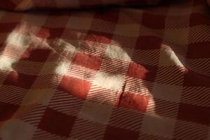 Sunlight is gently casting soft shadows across a beautiful red checkered fabric surface photo
