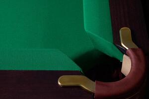 A CloseUp View of a Corner of a Billiards Pool Table Featuring Green Felt and Elegant Brass Details photo