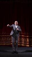 Showman dances on a stage. Senior male entertainer, presenter or actor on stage. Selective focus on a male in suit. Vertical video