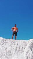 Sportsman standing on cliff of mountain. Man with naked torso standing on top of mountain and enjoying nature. Vertical video