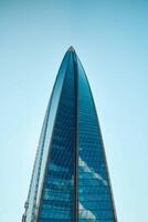 A stunning modern skyscraper stands tall against a clear, cloudless blue sky above photo
