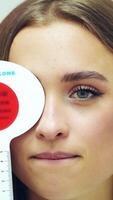 Woman having eye exam. Beautiful girl checks vision at ophthalmologist with one eye closed. Vertical video