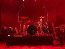 Exciting stage setup with drums and guitar under red lights, creating a thrilling atmosphere photo