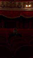 Man stands up from a red theater chair and throws medical mask away. Visitor in empty hall. Stop pandemic concept. Vertical video