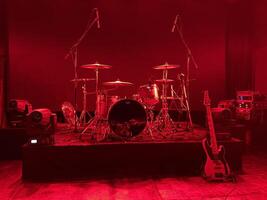 A beautifully illuminated stage setup featuring both drums and guitar for a live performance photo