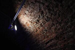An Illuminated Brick Wall Standing Out Distinctly Within a Dark Environment Setting photo