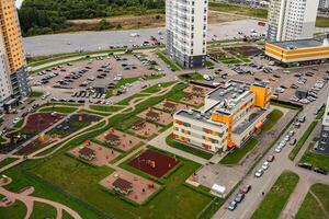 Aerial view of a modern residential complex featuring a playground, parking, and gardens photo