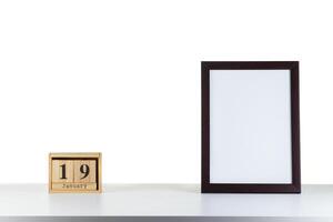 Wooden calendar 19 January with frame for photo on white table and background