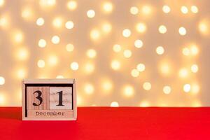 wooden calendar 31 december on red background and lights background photo