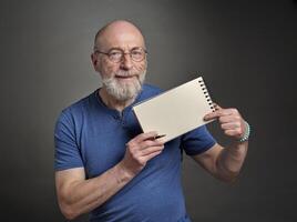 senior man is holding a blank sheet of paper and a pen, presentation concept photo