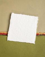 small sheet of blank white Khadi rag paper from India against abstract landscape in pink and green pastel tones photo