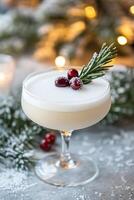 Crystal coupe glass holds frothy cocktail, garnished with rosemary and sugared cranberry. photo