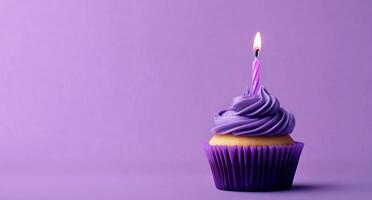 A purple cupcake with a single candle on top photo