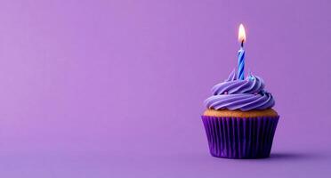 A purple cupcake with a single candle on top photo