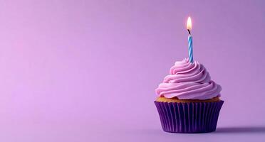 A cupcake with a single candle on a purple background photo