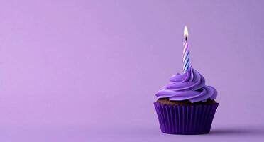 A cupcake with a purple frosting and a single candle photo