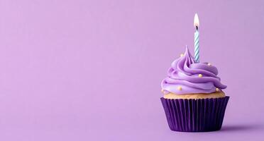 A cupcake with a single candle on a purple background photo