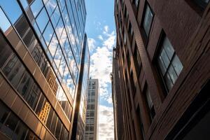 A view between tall buildings reflecting the sky and clouds. photo