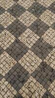 Old checkered stone pavement forming geometric pattern in Prague. Vertical mobile photo