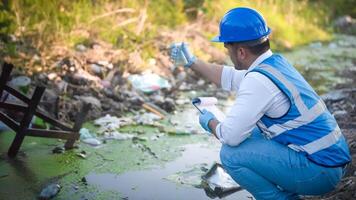 Water resource experts check the water quality in a community canal contaminated with garbage in the canal. photo