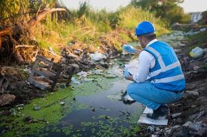 Water resource experts check the water quality in a community canal contaminated with garbage in the canal. photo