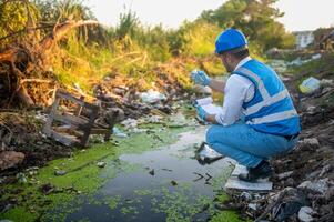 Water resource experts check the water quality in a community canal contaminated with garbage in the canal. photo