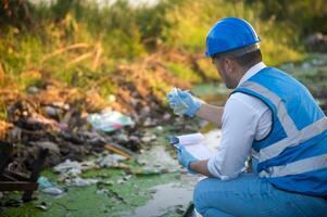 Water resource experts check the water quality in a community canal contaminated with garbage in the canal. photo