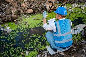 Water resource experts check the water quality in a community canal contaminated with garbage in the canal. photo