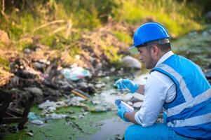 Water resource experts check the water quality in a community canal contaminated with garbage in the canal. photo