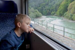 Little boy looks thoughtfully out the train window photo