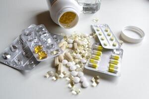 A lot of different vitamins and tablets in packages and without on a white table photo