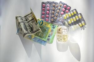 Jelly capsules and hard tablets of vitamin D on dollar bills on a white table photo