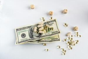 Jelly capsules and hard tablets of vitamin D on dollar bills on a white table photo