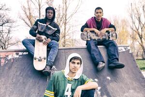 group of young adults sitting on a ramp with skateboard photo