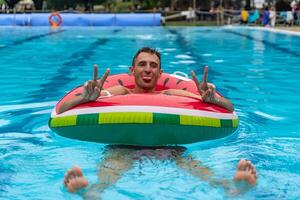 portrait of young adult in swimsuit having fun in the water of a swimming pool inside a life ring photo