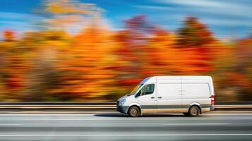 A white van driving on the highway with autumn trees in the background photo