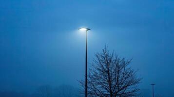 A street light is on a pole in the middle of a foggy night photo