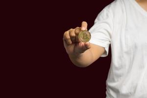 Close-up of hand holding a bitcoin coin while standing over a red background photo