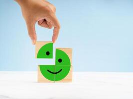 Hand holding a wooden cube with the happy green face icon to give the best satisfaction to the service photo