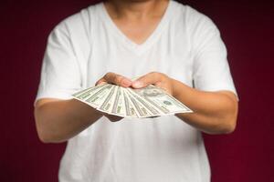 Close-up of hands holding US banknotes while standing on a red background photo
